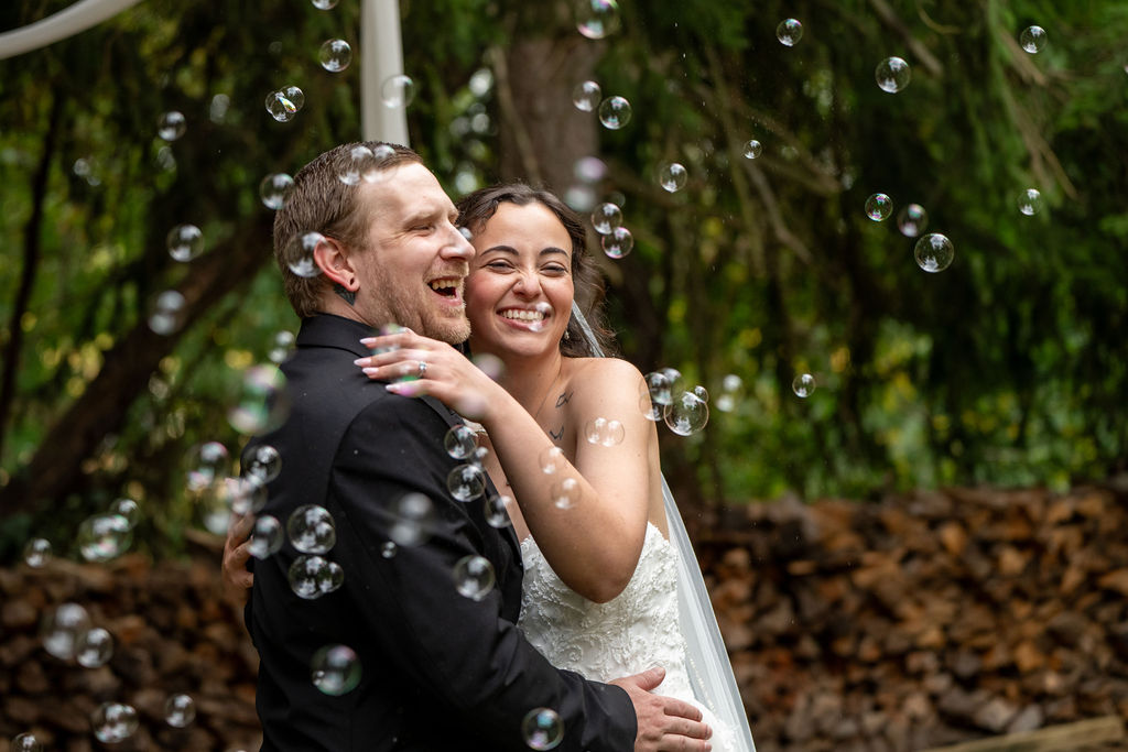 Life In Focus Maine Wedding Photographers, bride and groom celebrate with enthusiastic smiles and bubbles floating by